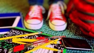 close up shot of kid’s Chucks standing among school supplies